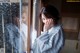 A woman in a blue and white kimono looking out of a window.