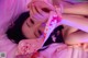 A woman laying on a bed with a pink light on her face.