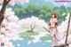 A woman stands by a cherry blossom tree near water, holding a sword.