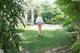 A woman walking down a path in a lush green garden.