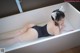 A woman in a bathing suit laying in a bathtub.