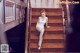 A woman in a white bodysuit sitting on a wooden staircase.