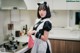 A woman in a maid outfit standing in a kitchen.