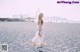 A woman in a white dress walking on a beach.