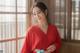 A woman in a red kimono posing by a window.