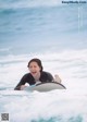 A woman laying on top of a surfboard in the ocean.