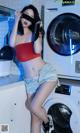 A woman standing in front of a washing machine.